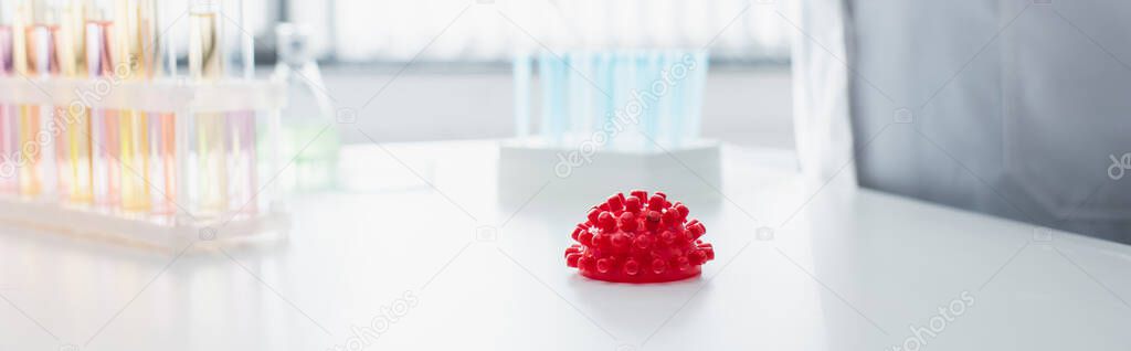 red coronavirus bacteria model near cropped virologist on blurred background, banner