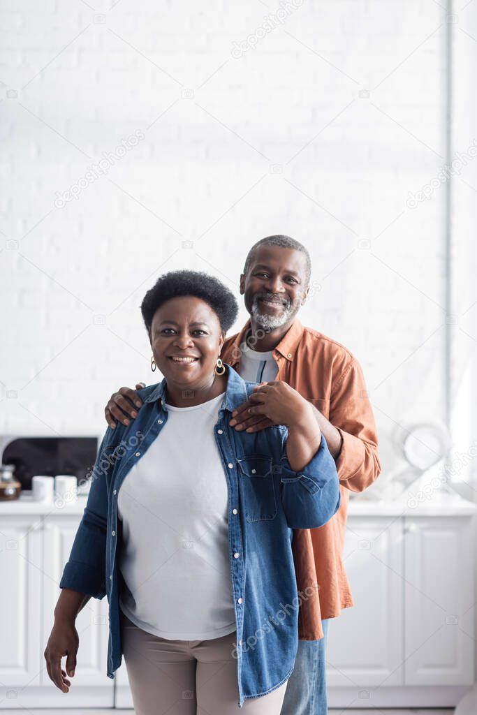 happy and senior african american man hugging cheerful wife