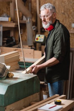 Sakallı marangoz marangozluk stüdyosunda çalışırken tahta tutuyordu.