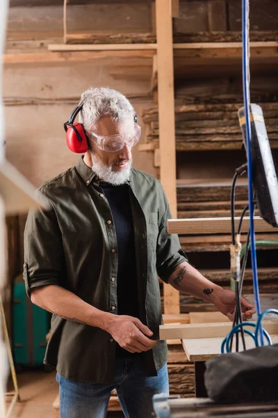 Ältere Holzarbeiter Betrachten Holzplanke Werkstatt — Stockfoto