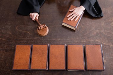 top view of cropped judge holding wooden gavel near collection of books clipart