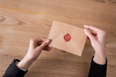 partial view of notary holding craft paper envelope sealed with wax stamp  clipart