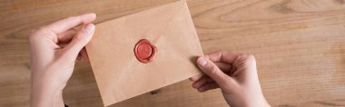 top view of craft paper envelope with wax stamp in hands of cropped notary, banner clipart