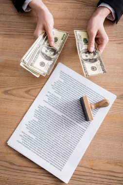 Sözleşme ve pulun yanındaki dolarları sayan noterlerin üst görünümü