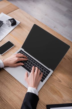 Akıllı telefonun yanında boş ekran ile dizüstü bilgisayarda yazılan kesilmiş noterin üst görünümü 