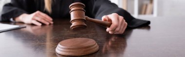 Bulanık arkaplan ve pankartta kırpılmış noterin elindeki tahta tokmağın seçici odağı