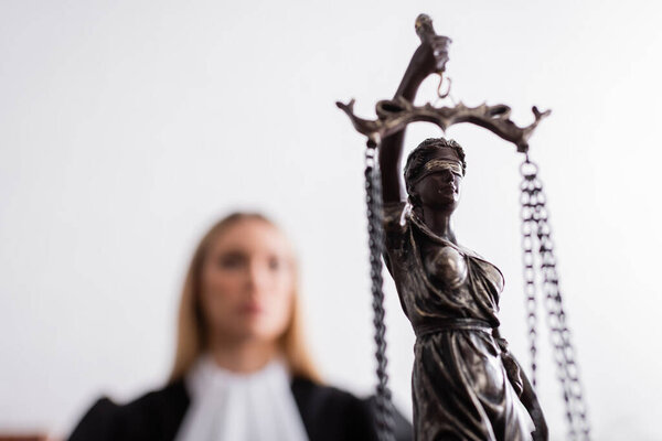 selective focus of themis statue near prosecutor on blurred background