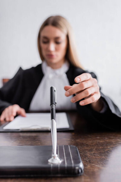 blurred prosecutor reaching pen while reading lawsuit on blurred background