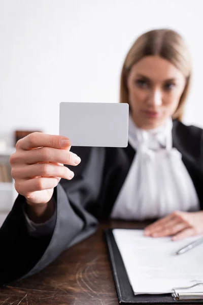 selective focus of empty business card in hand of prosecutor on blurred background