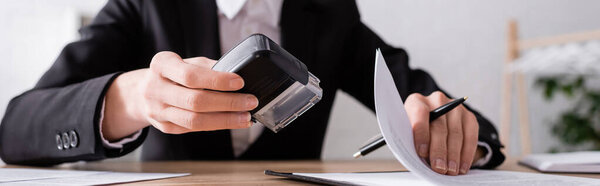 обрезанный вид размытого нотариуса со штампом, ручкой и контрактом, баннером