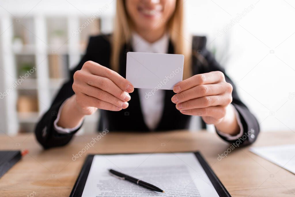 partial view of blurred notary holding blank business card 