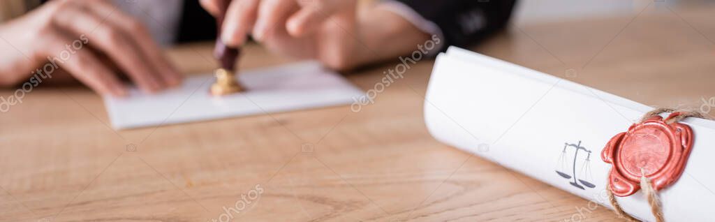 cropped view of blurred notary with stamper near rolled contract with wax seal, banner