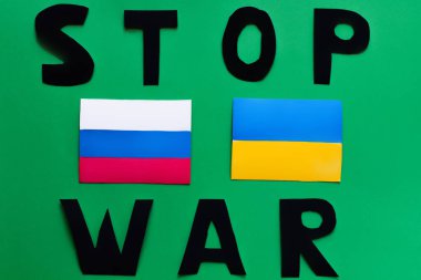 Savaş durdurma yazıları ve yeşil arka planda Ukrayna ve Rusya bayrakları 