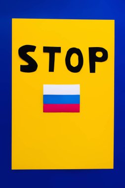Top view of stop lettering and russian flag on blue and yellow background  clipart