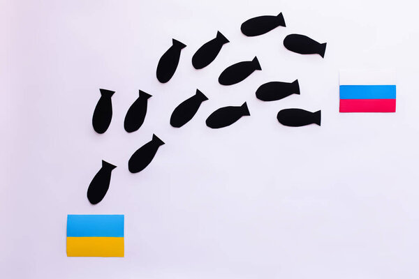 Top view of paper bombs between ukrainian and russian flags on white background 