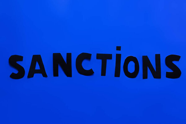 Top view of sanctions lettering on blue background 