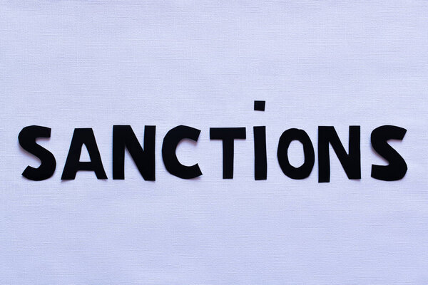 Top view of sanctions paper lettering on white background, war in ukraine concept 