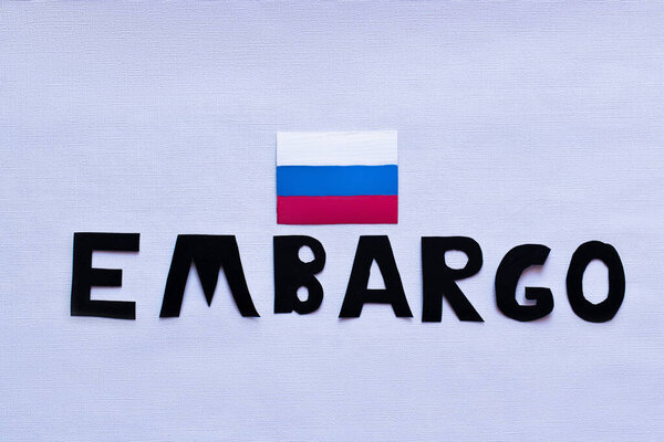 Top view of russian flag and embargo lettering on white background, war in ukraine concept 
