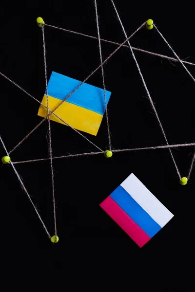 黒に隔離された糸でプッシュピンの近くのウクライナとロシアの旗のトップビュー — ストック写真