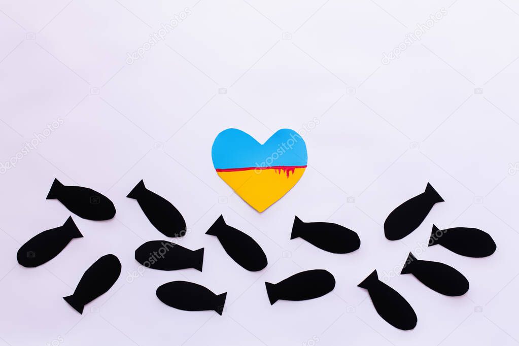 Top view of ukrainian flag with blood in heart shape near paper bombs on white background 