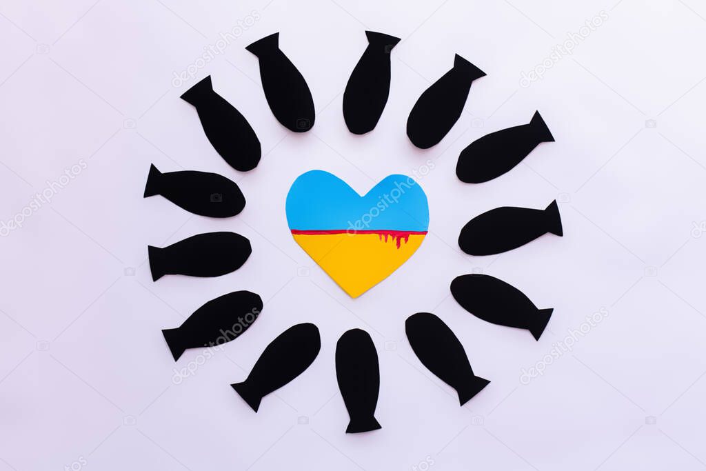 Top view of ukrainian flag in heart shape in frame from paper bombs on white background 