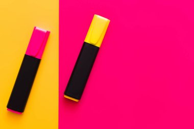 top view of colorful marker pens on pink and yellow background  clipart