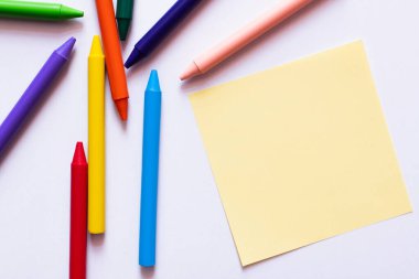 Beyaz üzerine sarı kağıda yakın renkli pastel boyaların üst görünümü 