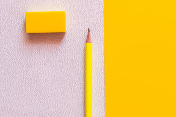 top view of pencil and eraser on white and yellow