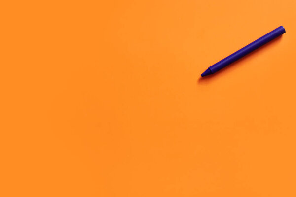 top view of purple crayon on bright orange background