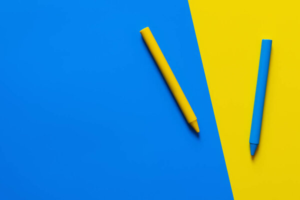 top view of crayons on blue and yellow background 
