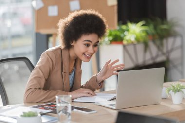 Pozitif Afro-Amerikan iş kadını laptopuyla ofiste video görüşmesi yapıyor. 