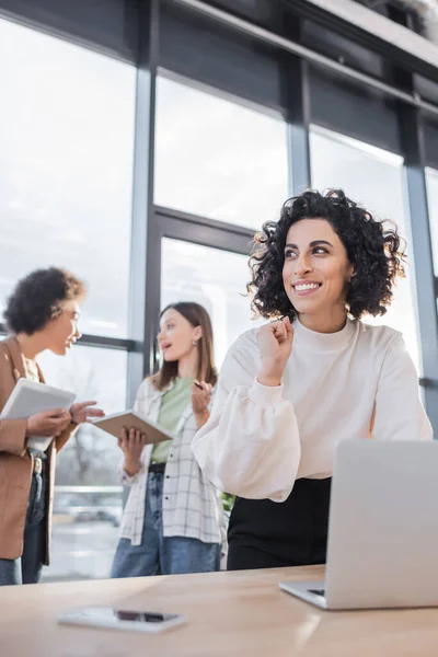 Excited Muslim Businesswoman Showing Yes Gesture Blurred Laptop Interracial Colleagues — Zdjęcie stockowe