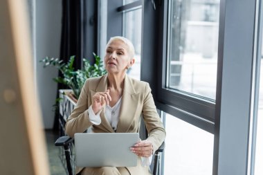 thoughtful economist in formal wear sitting with laptop in office