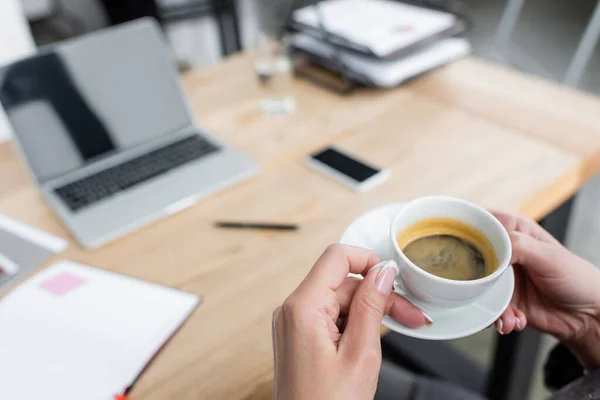 Cropped View Businesswoman Coffee Cup Blurred Gadgets Desk — kuvapankkivalokuva