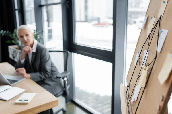 Blurred Banker Sitting Workplace Looking Corkboard Paper Notes — Zdjęcie stockowe