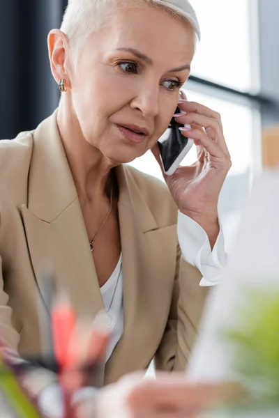 Concentrated Banker Talking Smartphone While Working Blurred Foreground — Zdjęcie stockowe