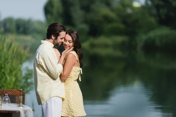 Homem Feliz Tocando Bochecha Mulher Sorridente Perto Lago — Fotografia de Stock