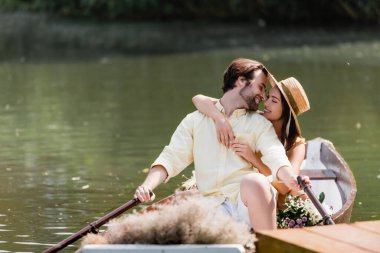 Hasır şapkalı mutlu genç kadın romantik tekne gezisi sırasında adama sarılıyor. 