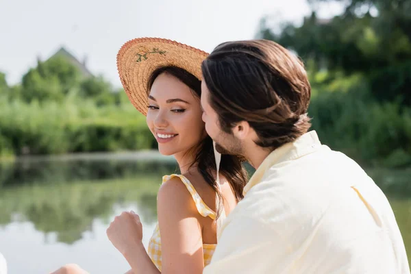 Blurred Man Whispering Ear Smiling Woman Straw Hat — Stock Photo, Image