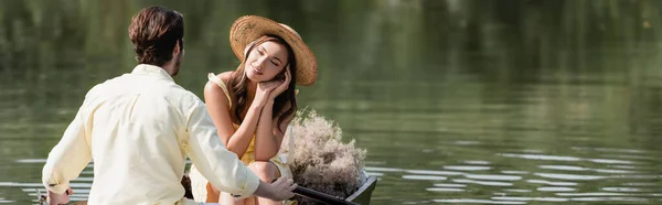 戴着草帽的梦幻女人在划船时看着浪漫的男友 一面横幅 — 图库照片