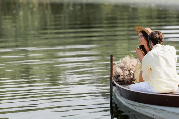 ボートに乗っている間に恋人の近くに見てわら帽子の笑顔の女性 — ストック写真
