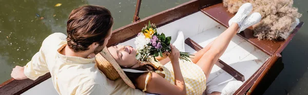 麦藁帽子の若い女性の高い角度のビュー花の花束を保持し 男とボートに横たわって バナー — ストック写真