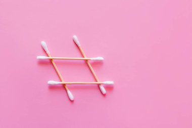 top view of grid made of cotton swabs on pink background