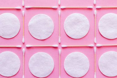 Pembe arka planda beyaz pamuk pedlerin ve kulak çubuklarının düz yatışı.