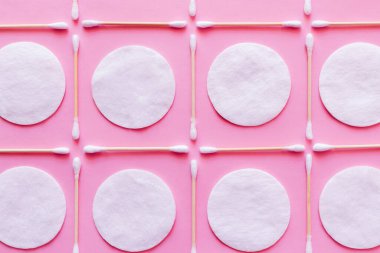 flat lay of white cotton pads and ear sticks on pink background, top view clipart