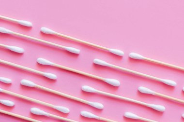 top view of diagonal lines of cotton swabs on pink background