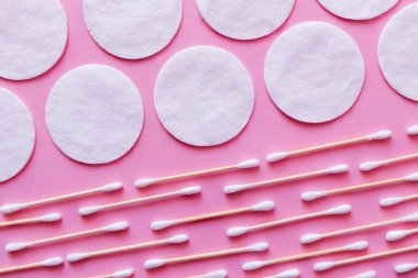 Pembe arka planda beyaz pamuk pedler ve kulak çubukları, üst görünüm
