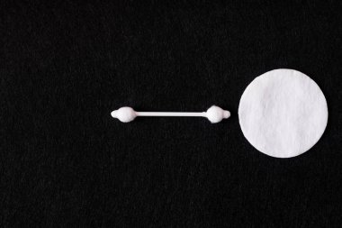 top view of white cotton pad and ear stick on black background