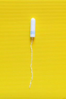 top view of hygienic tampon on bright yellow textured background