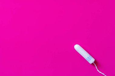 top view of hygienic tampon on purple background with copy space